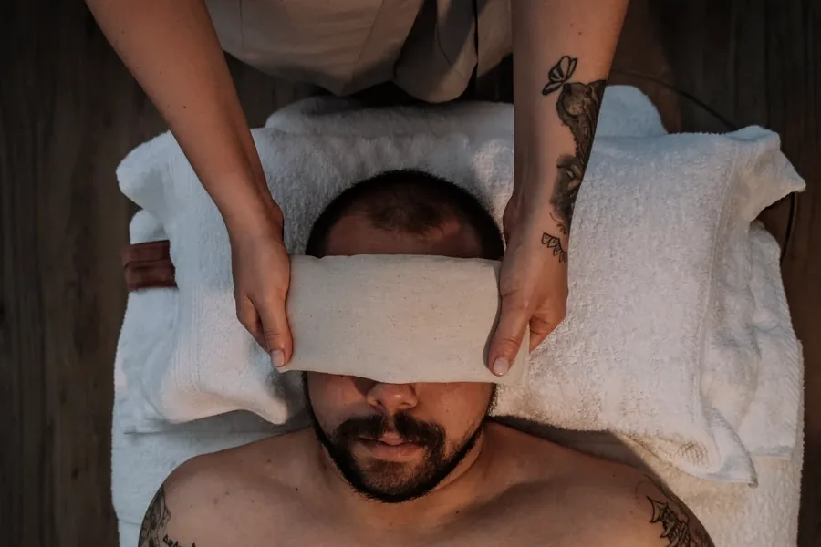 Mayara Mazzoni a colocar uma almofada de relaxamento sobre os olhos de um cliente